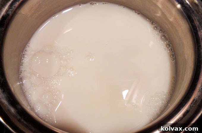 Pouring fresh milk into a saucepan, ready to be transformed into Olaf's Warm Hug Hot Vanilla Milk.