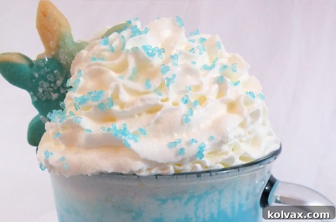 Olaf's Warm Hug Hot Vanilla Milk, topped with whipped cream and blue sparkling sugar, ready to be enjoyed.
