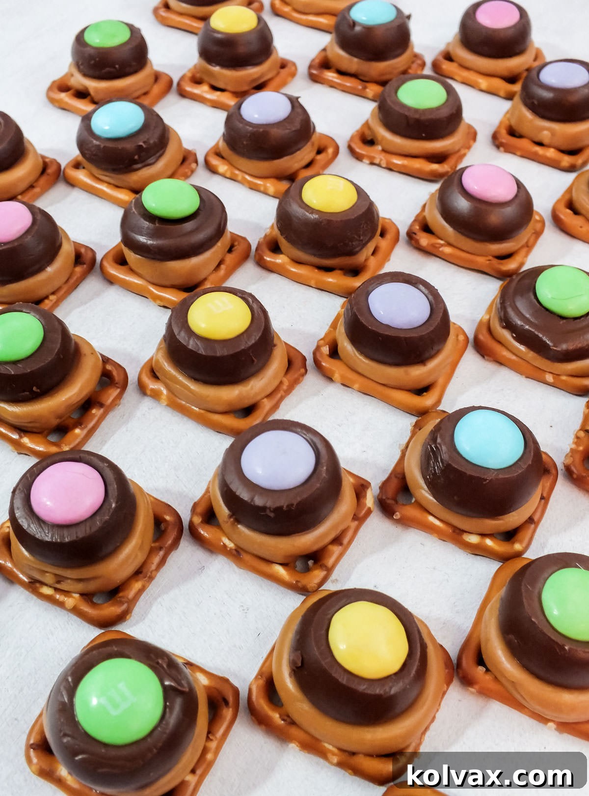 Closeup on rows of Spring Caramel Pretzel Bites sitting on a clean white surface, showcasing their perfect layers.