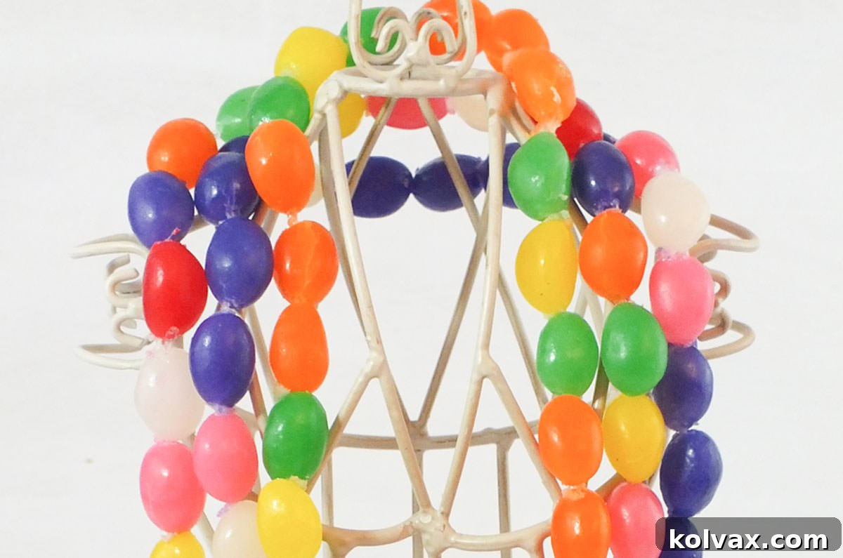 Closeup of three colorful DIY Jelly Bean Easter Necklaces hanging on a necklace stand, showcasing various patterns and vibrant colors, perfect for Easter celebrations.