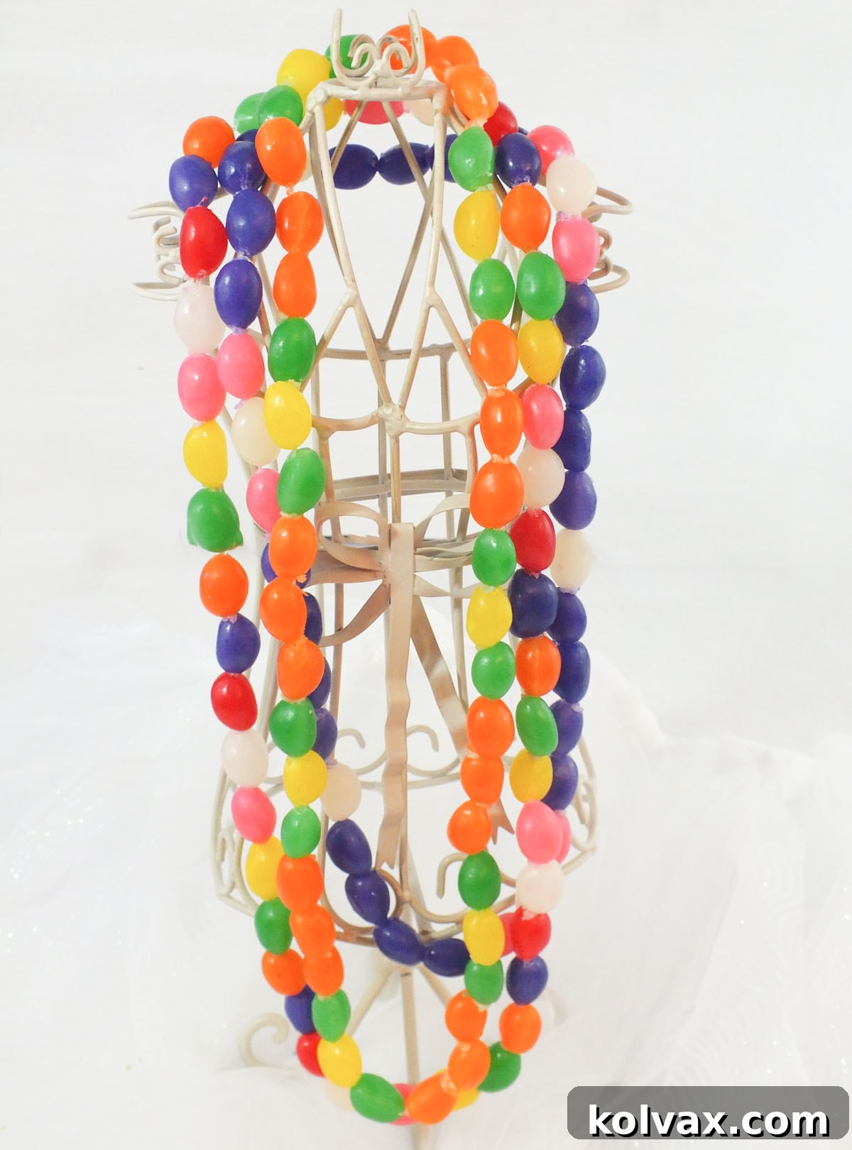 Close up of three finished DIY Jelly Bean Necklaces hanging on a necklace holder, showcasing their colorful designs and readiness for wear or gifting.