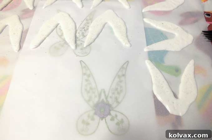 Piping delicate Tinkerbell fairy wings with white royal icing.