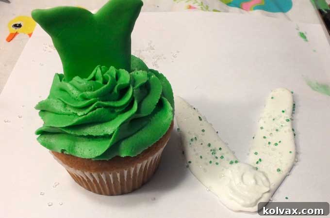 Applying a drop of royal icing to attach Tinkerbell wings to the dress.