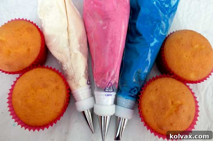 Best Buttercream Frosting prepared in vibrant pink, blue, and classic ivory shades, ready for decorating Frozen cupcakes.