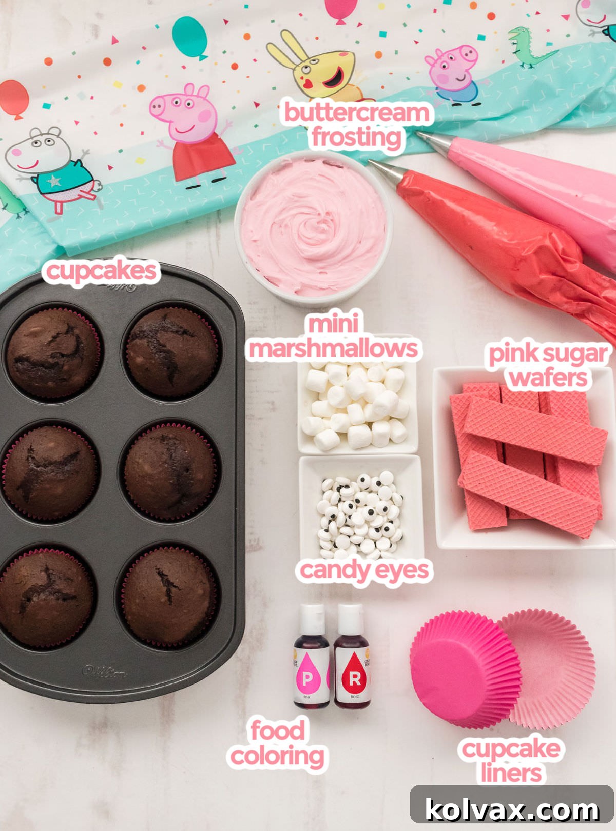 All the essential ingredients for Peppa Pig Cupcakes, including baked cupcakes, buttercream frosting, various food colorings, pink sugar wafers, mini marshmallows, candy eyes, and cupcake liners, neatly arranged on a clean white surface.