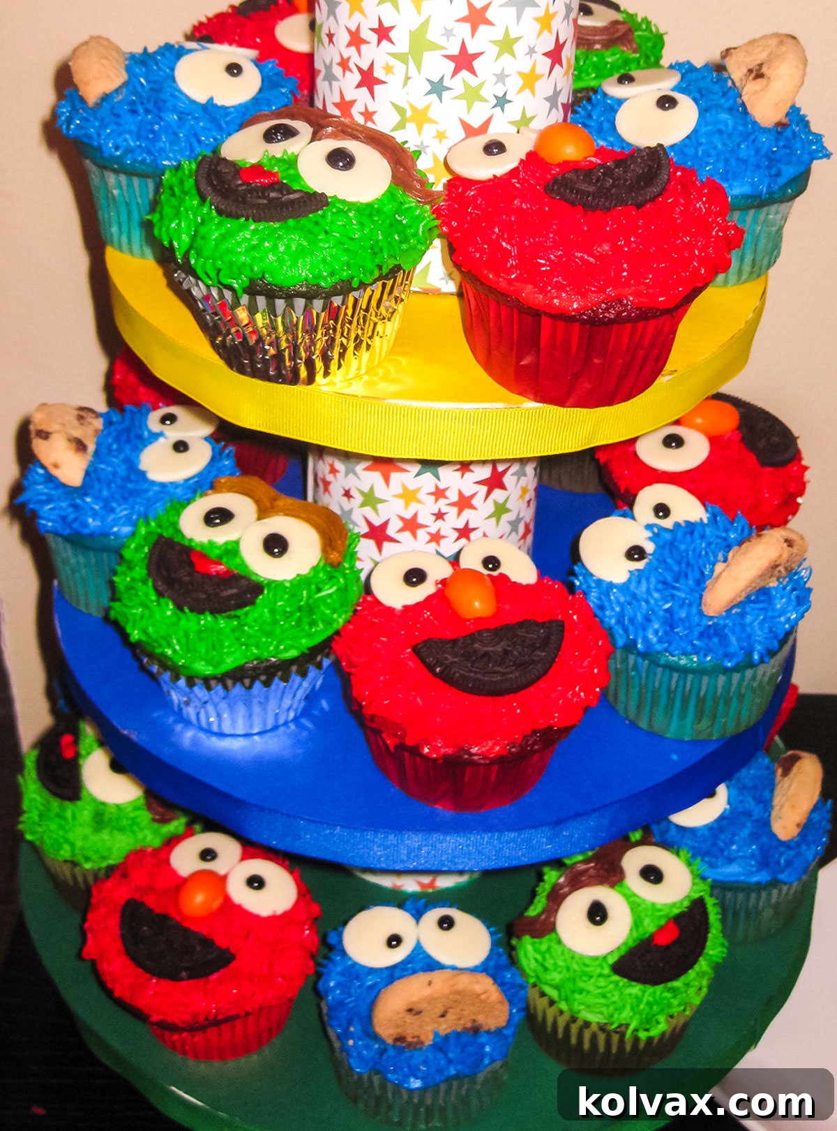 Closeup on a colorful Cupcake Tower filled with Sesame Street Cupcakes including Elmo Cupcakes, Cookie Monster Cupcakes and Oscar the Grouch Cupcakes. The tiered tower showcases a vibrant array of carefully decorated character cupcakes.
