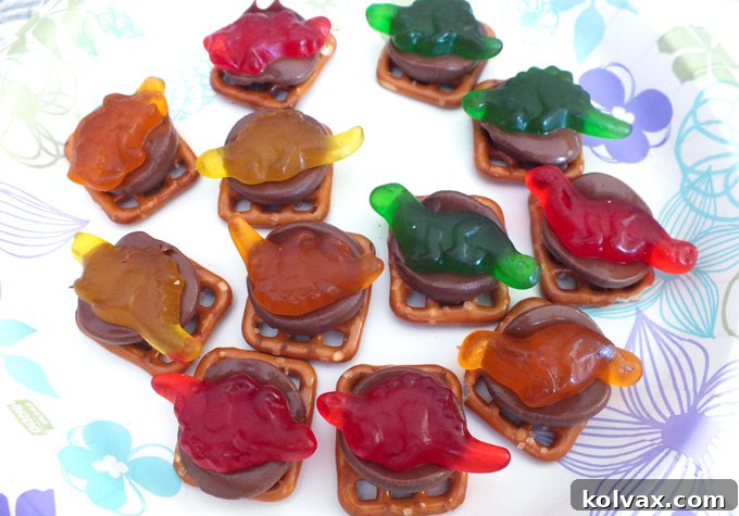Pressing Gummy Dinosaurs onto Melted Chocolate: The Final Touch for Fun Pretzel Bites