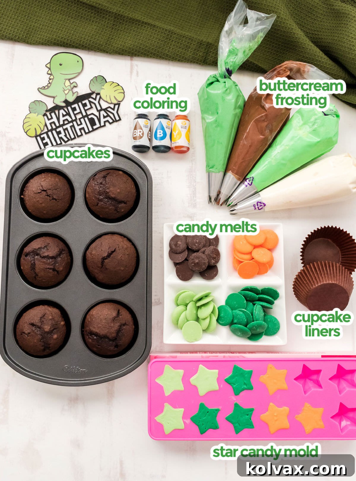 A comprehensive display of all necessary ingredients for crafting Dinosaur Cupcakes, including baked cupcakes, creamy buttercream frosting, colorful candy melts, food coloring, and a star-shaped candy mold.
