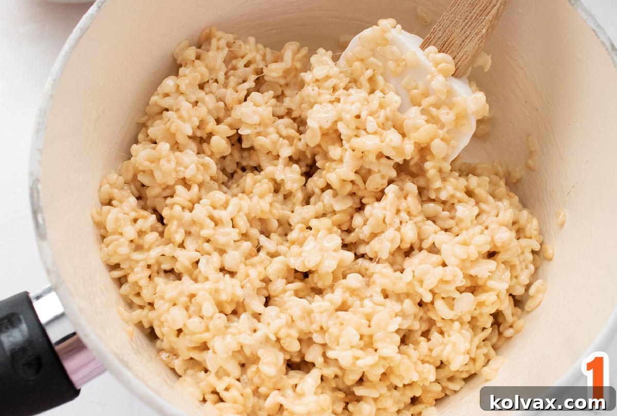 White pan filled with Rice Krispie Treat mixture and a wooden spoon.