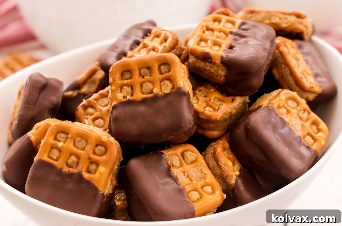 Closeup on a white serving bowl filled with Chocolate Peanut Butter Pretzel Bites sitting on a white table in front of another white bowl, showcasing their delicious appeal.