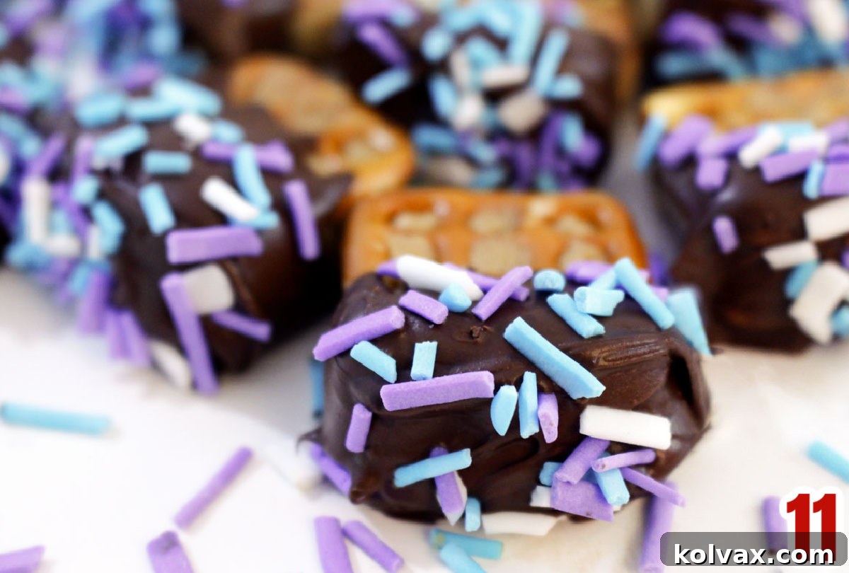 Closeup on Chocolate Dipped Peanut Butter Pretzels covered in colorful sprinkles for parties, in a white bowl.