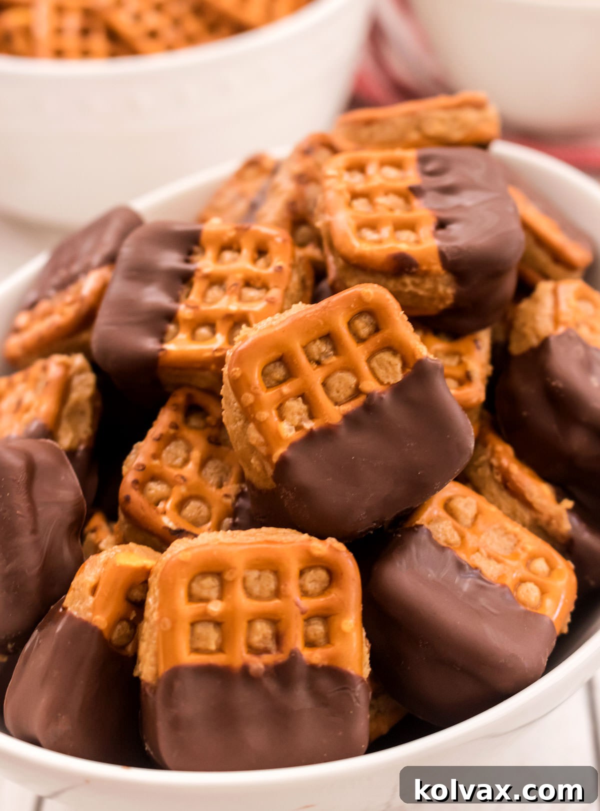 Closeup on a white serving bowl filled with Chocolate Peanut Butter Pretzel Bites, ready for serving.