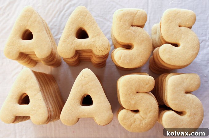 Freshly baked sugar cookies in 'A' and '5' shapes, golden brown and ready for frosting.