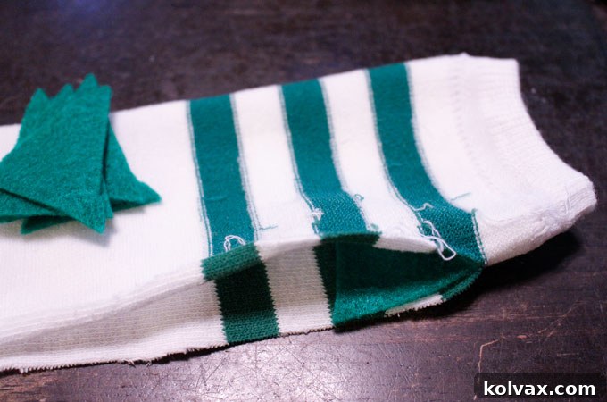Detailed view of arranging felt dinosaur spikes along the inside of the sock's cut seam, ensuring even spacing before pinning.