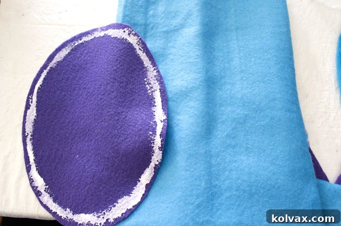 Adding an oval-shaped felt piece to the front of the dinosaur party favor bag, representing the distinctive underbelly of the dinosaur.