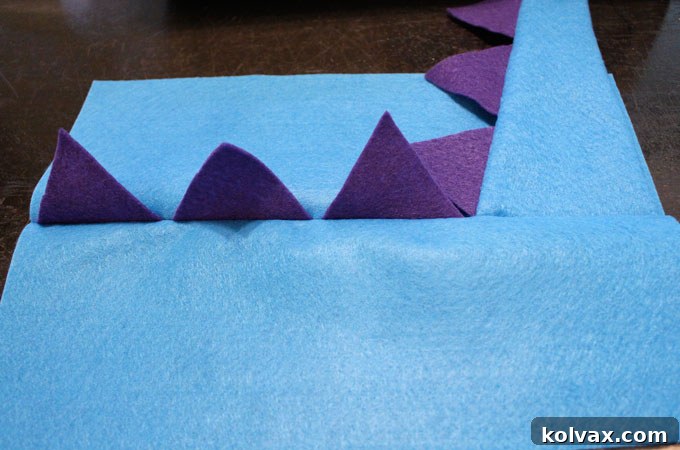 The successfully assembled back panel of the dinosaur party favor bag, showcasing the securely sewn-in tail and a row of spikes.