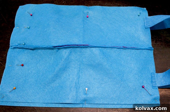 The front and back panels of the dinosaur party favor bag, now with securely attached felt handles, ready for final assembly.