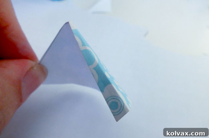 Folding down one edge of the cut-out paper party hat for gluing.