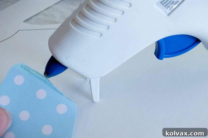 Applying a bead of hot glue along the folded edge of the party hat.