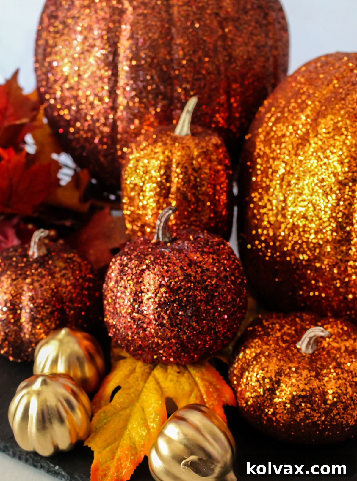 Glamorous Glitter Pumpkin Decor 6 Closeup on a stack of Orange DIY Glitter Pumpkins of various sizes sitting on a black surface, demonstrating how they can be artfully arranged.