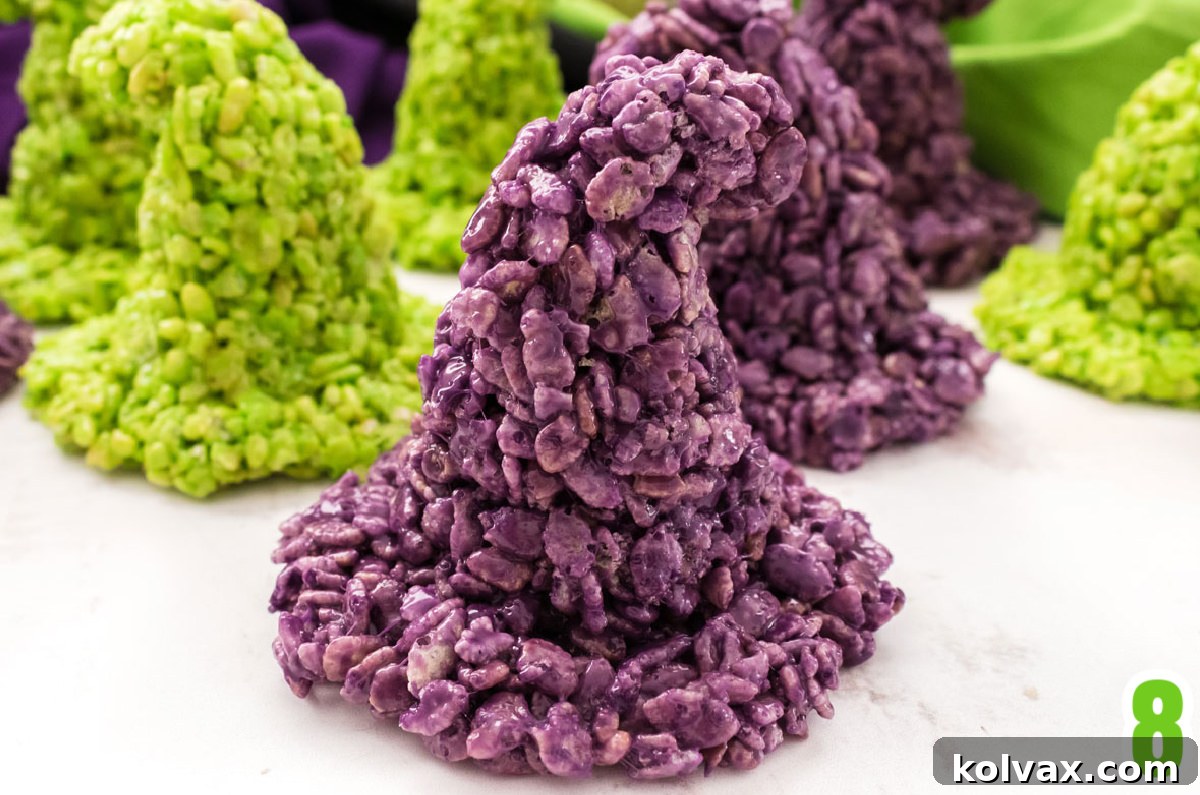 Enchanted Krispie Witch Hats 6 Closeup on seven purple and green Rice Krispie Treat molded into Witch Hats, sitting on a white table.