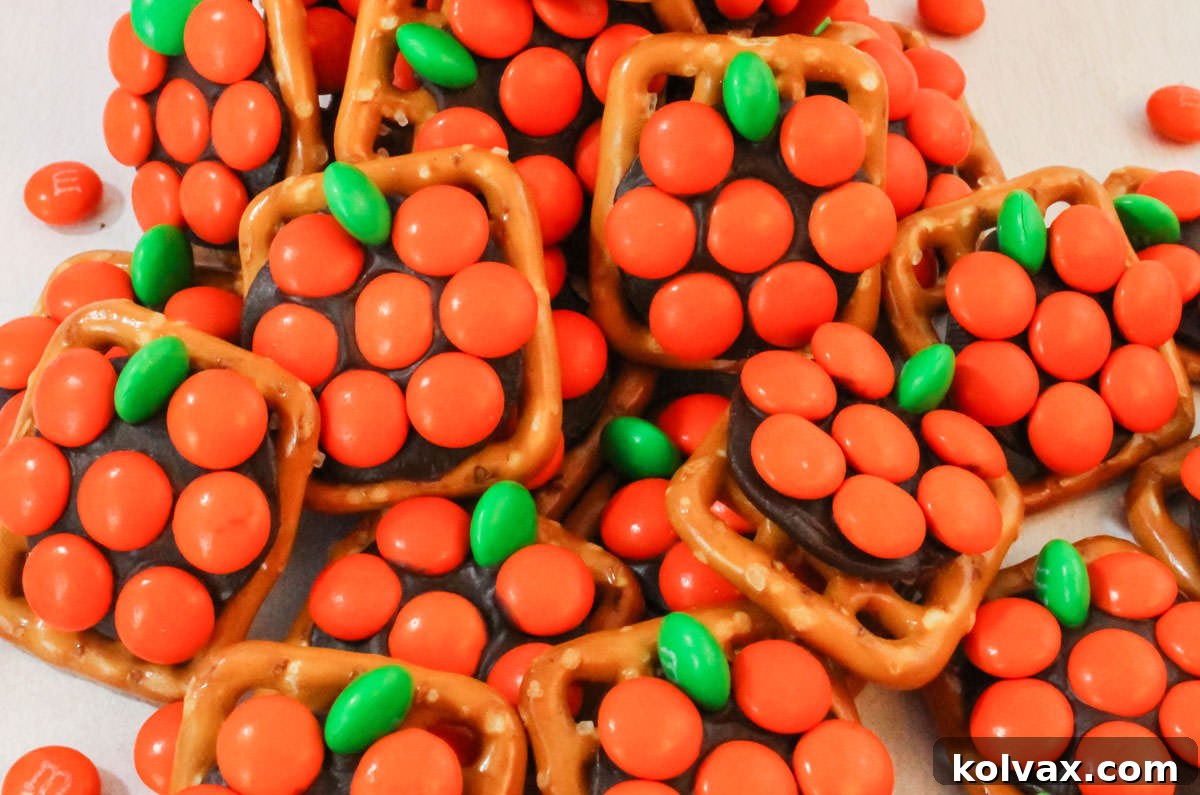 Closeup on a stack of Pumpkin Pretzel Bites laying on a white table surrounded by orange M&M's.