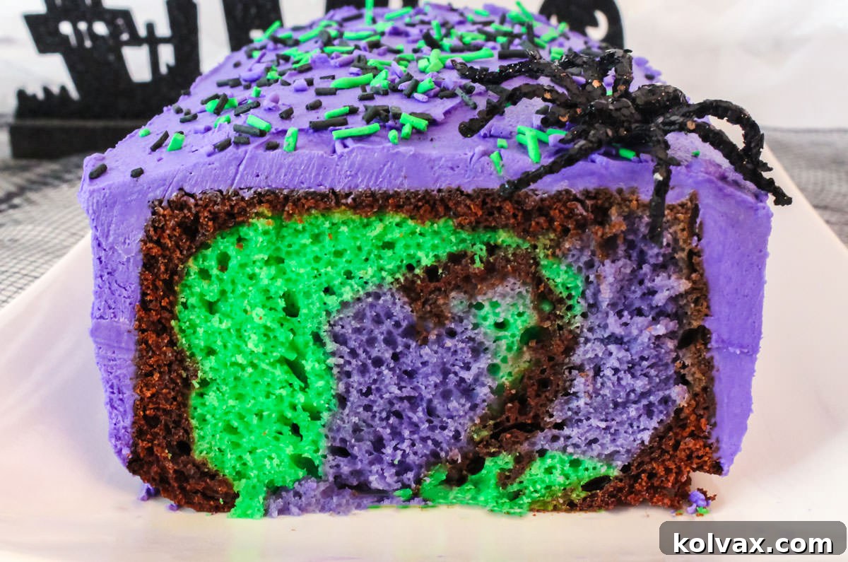 Closeup on a Bewitched Marble Cake that has a sliced removed so you can see the Halloween color marble effect inside the cake.