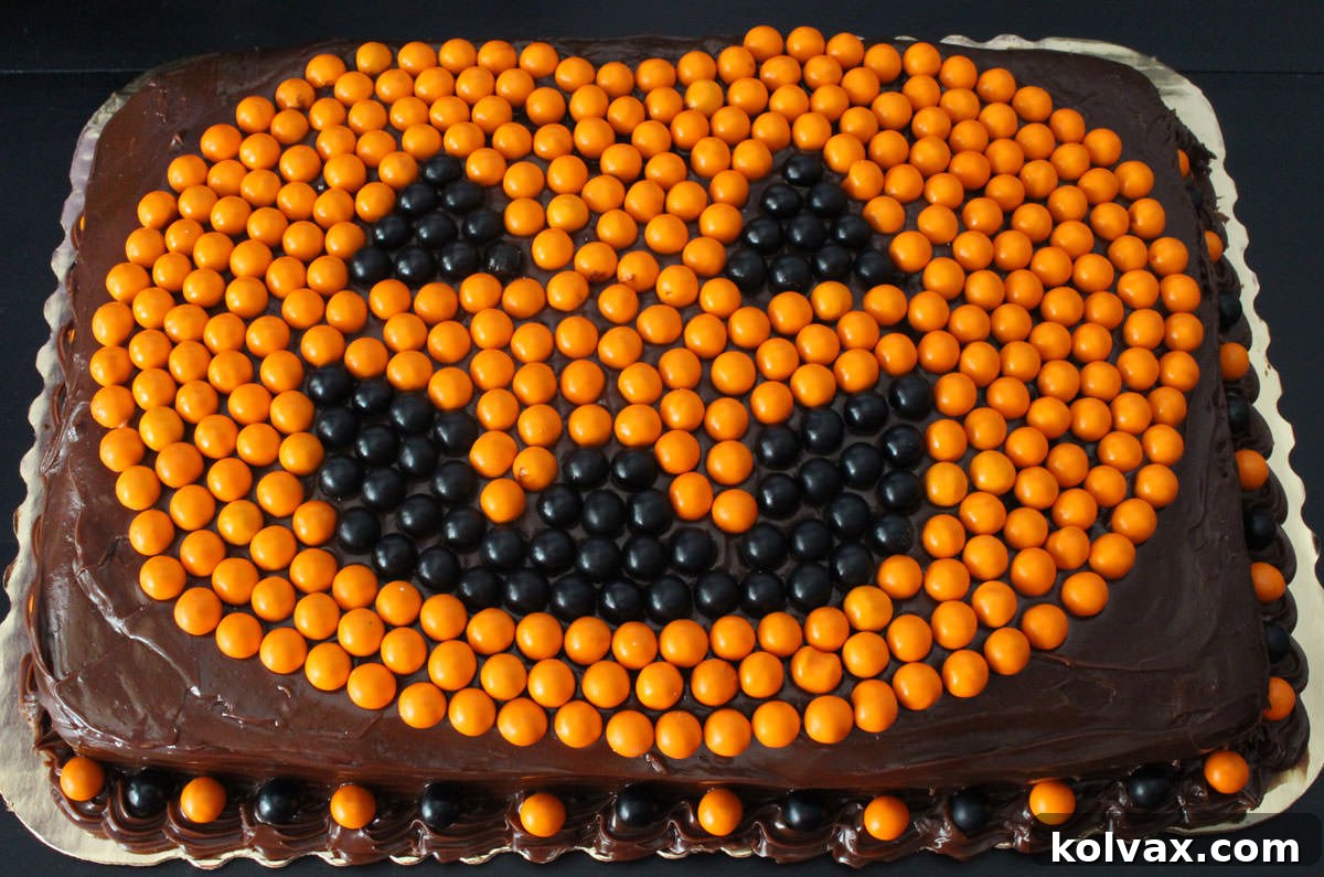Closeup of an Easy Halloween Cake featuring a festive Jack o' Lantern design made with orange and black Sixlets, perfect for a Halloween party.