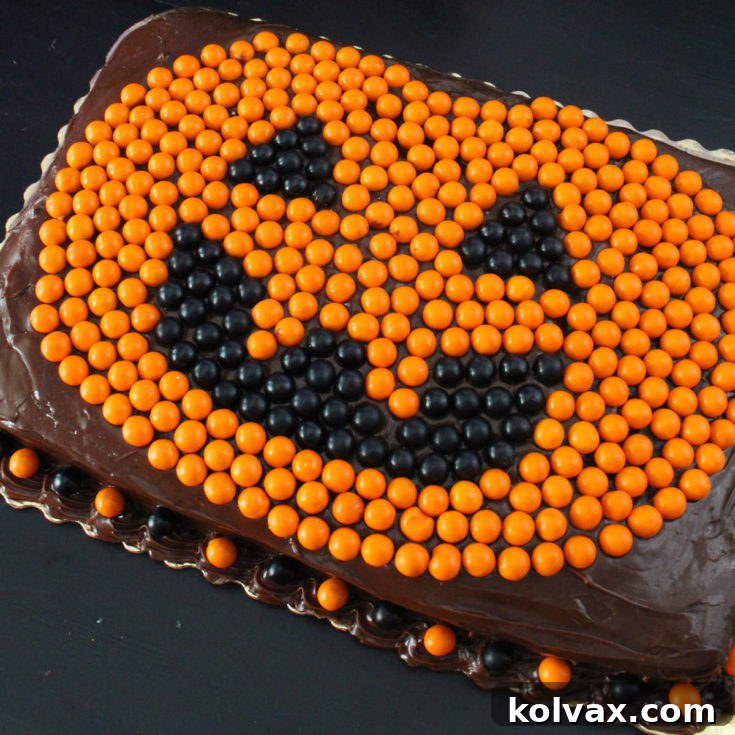 Easy Halloween Cake, a festive Jack O' Lantern decorated with Sixlets on a chocolate sheet cake.