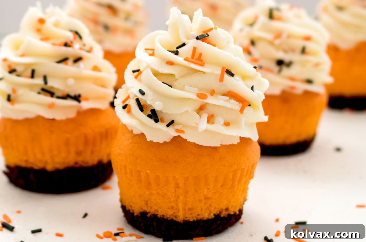 Closeup on six Brownie Cupcakes sitting on a white table surrounded by Halloween sprinkles, showcasing their vibrant frosting and festive decorations.
