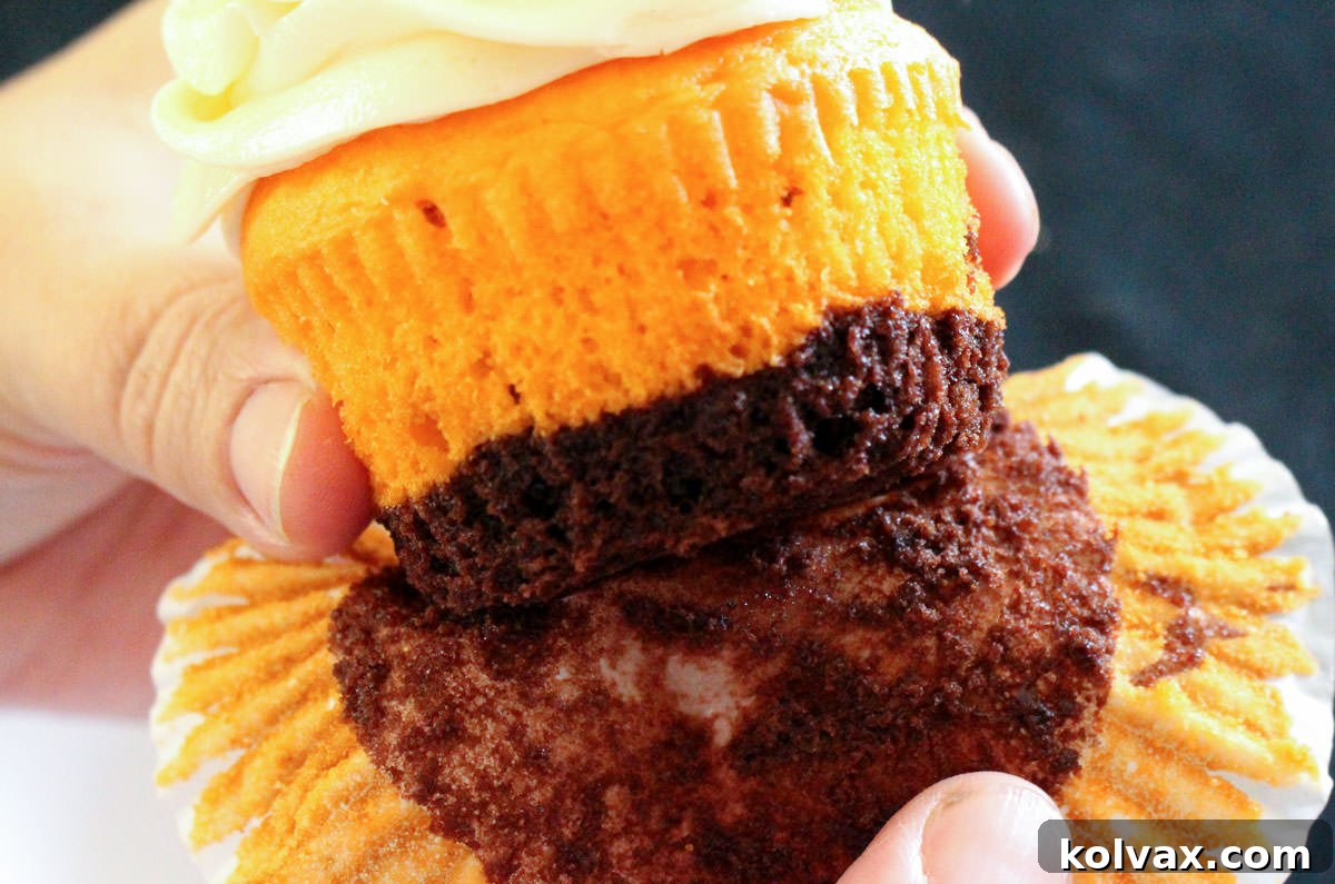 Closeup of a Brownie Cupcake in the process of having its cupcake liner carefully removed, showing the distinct brownie and cake layers.