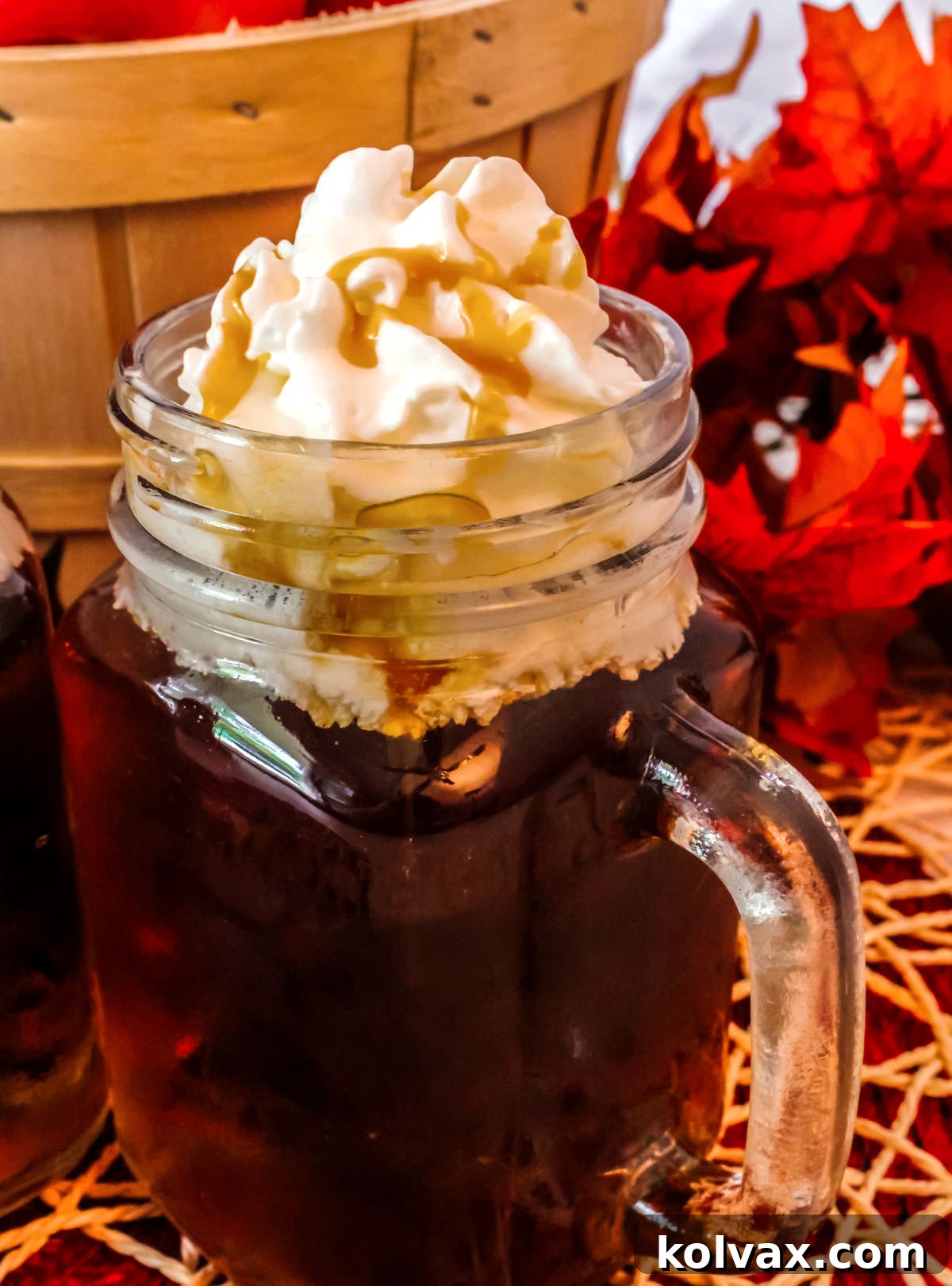 Closeup on a glass mug filled with Caramel Apple Cider topped with Whipped Cream and Caramel sauce.