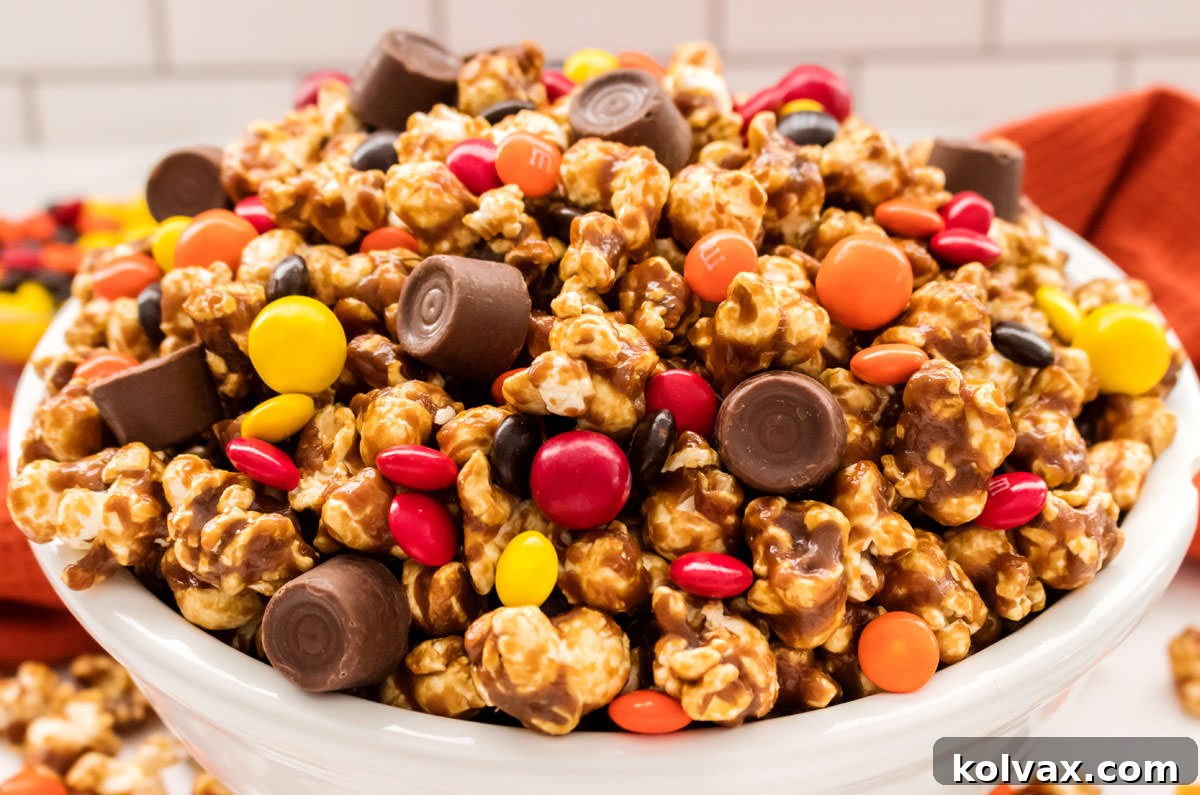 Closeup on white bowl filled with Harvest Caramel Corn sitting on a white table with an orange table linen in the background.