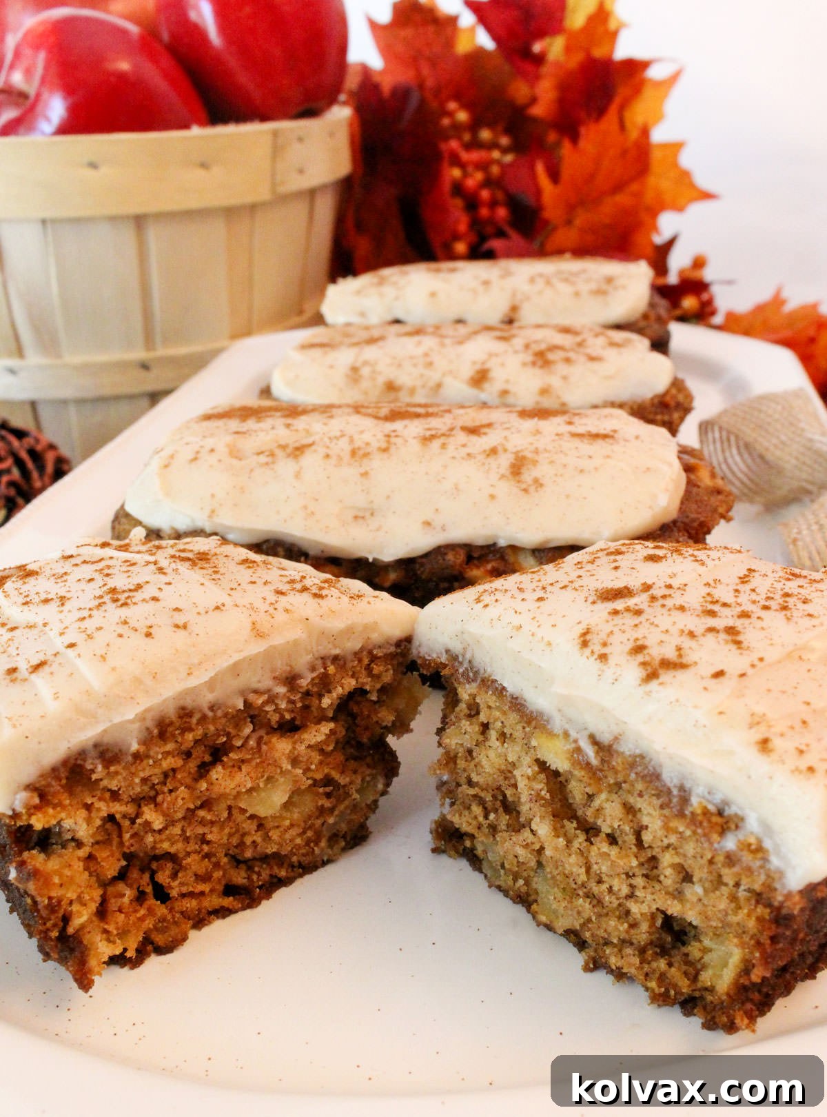 White serving platter showcasing four elegantly frosted Apple Bread Mini Loaves, each topped with a delicate dusting of cinnamon.