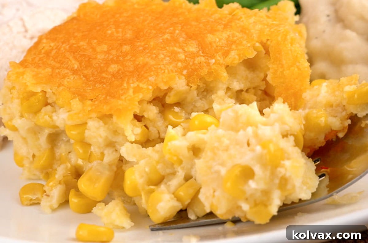 Closeup on a serving of Corn Casserole on a Thanksgiving dinner plate filled with turkey, mashed potatoes and vegetables, ready to be enjoyed as a festive holiday side dish.