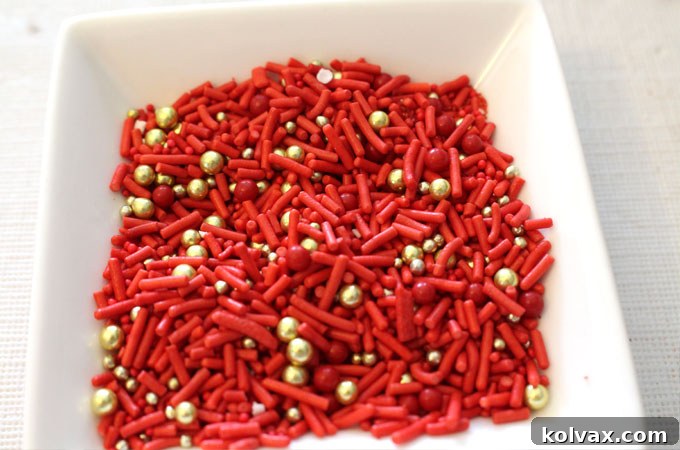 Vibrant holiday sprinkle mix featuring dazzling red jimmies and shimmering gold sugar pearls.