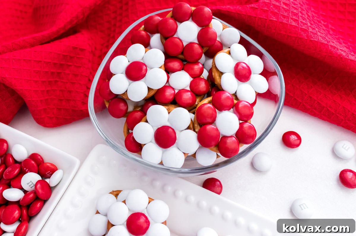 Closeup on a batch of Holiday Poinsettia Flower Pretzel Bites arranged on a white table with a red kitchen towel.