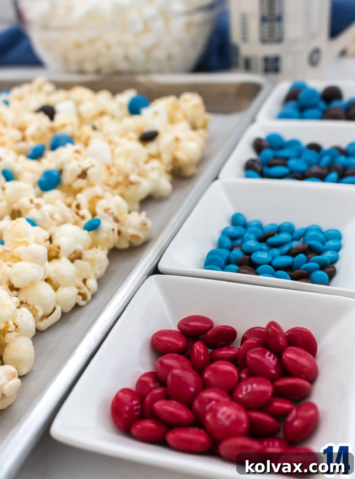 A vibrant closeup of four small ramekins filled with a variety of M&M's candies in red, blue, and brown, ready to be mixed into the Star Wars Popcorn.