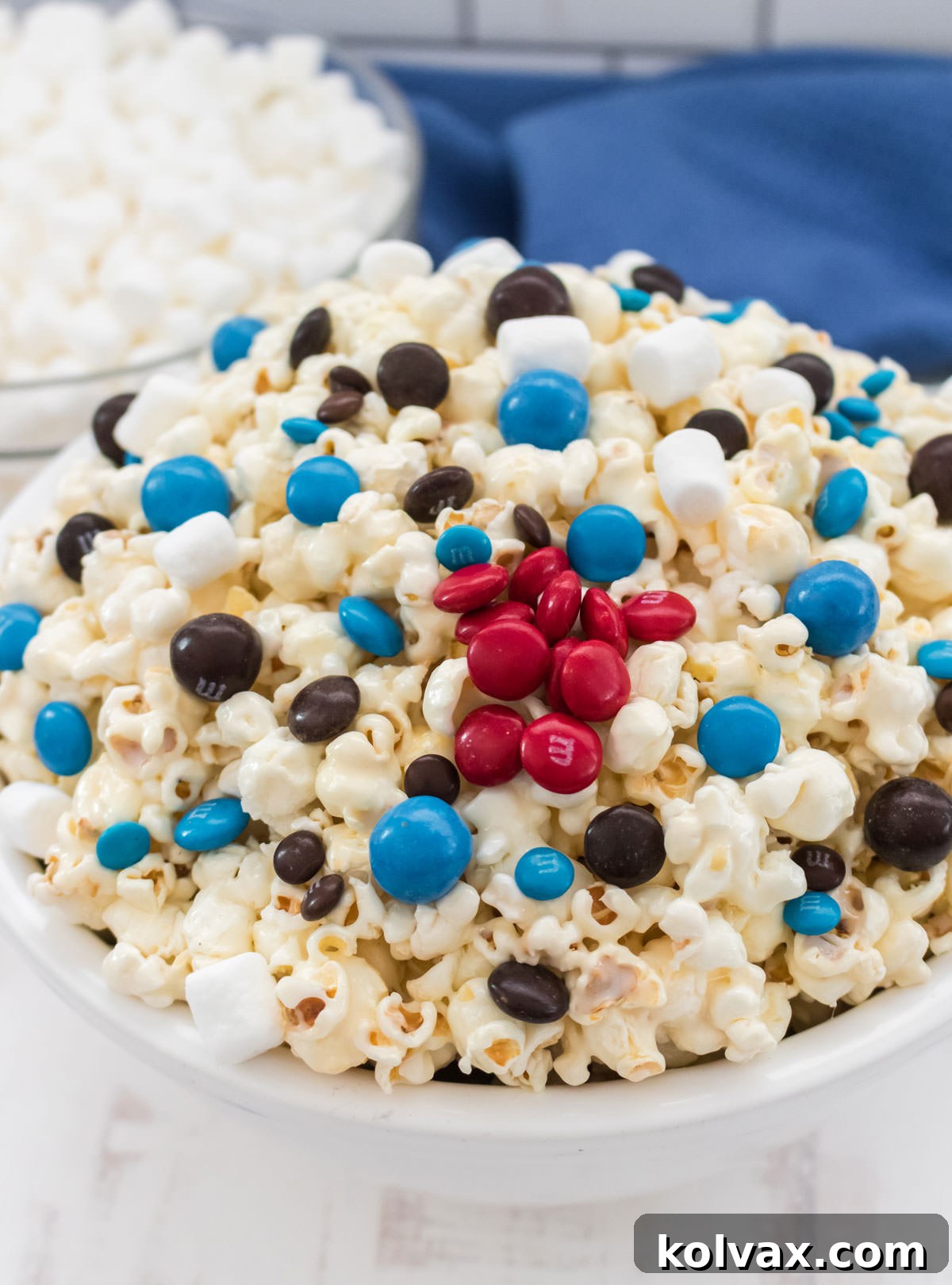 A close-up view of a pristine white serving bowl filled to the brim with festive Star Wars Popcorn, showcasing the colorful candy and gooey marshmallow coating. Ready to serve at any gathering.