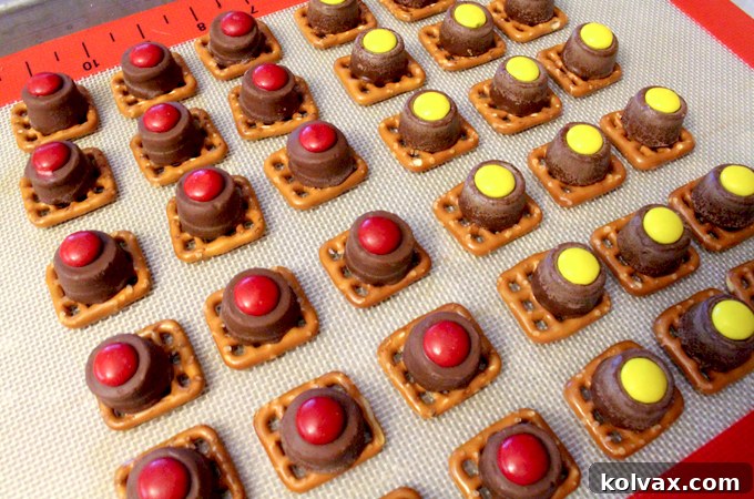 Adding Red and Yellow M&M's to Melted Rollo on Pretzels