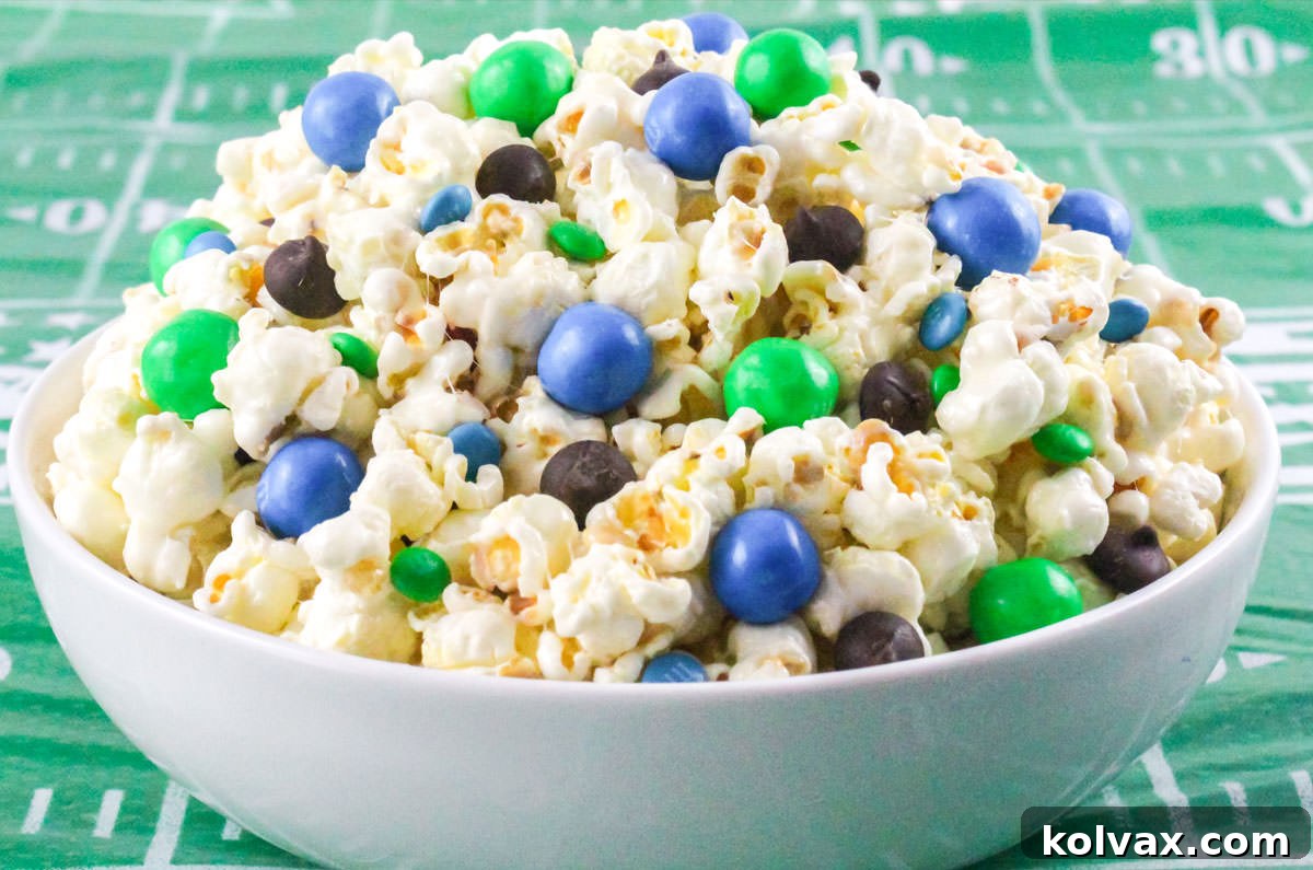 A white bowl filled with vibrant Seattle Seahawks Popcorn, featuring blue and green candies, sitting on a festive green football-themed tablecloth, ready for game day.