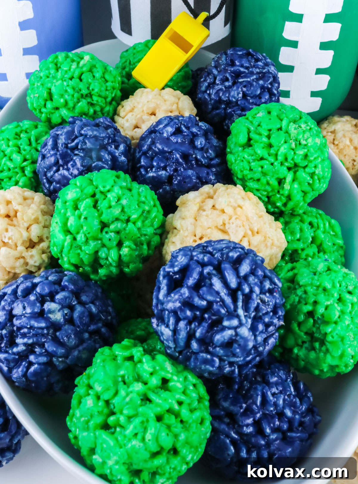 Closeup on a white bowl filled with Seattle Seahawks Rice Krispie Bites sitting next to football decorations.