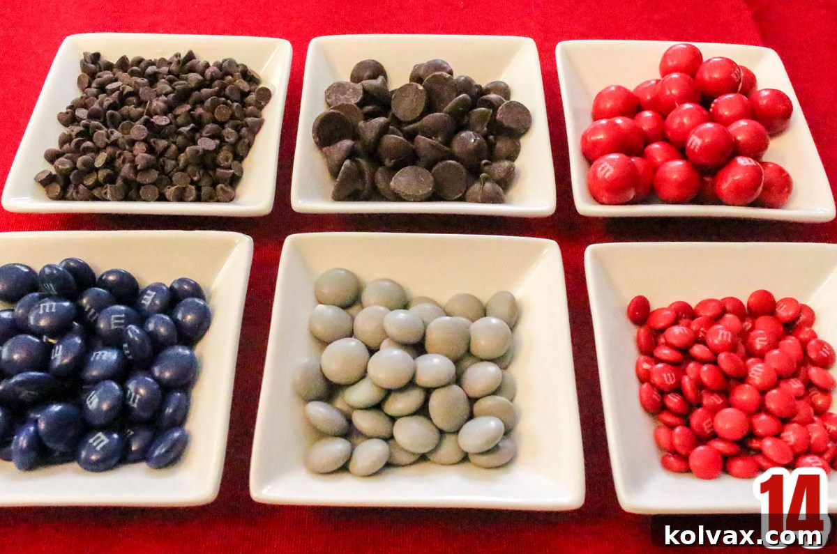 Six white ramekins arranged in two rows on a red tablecloth, filled with various Red, Blue, and Grey M&M's and Chocolate Chips for the themed popcorn.