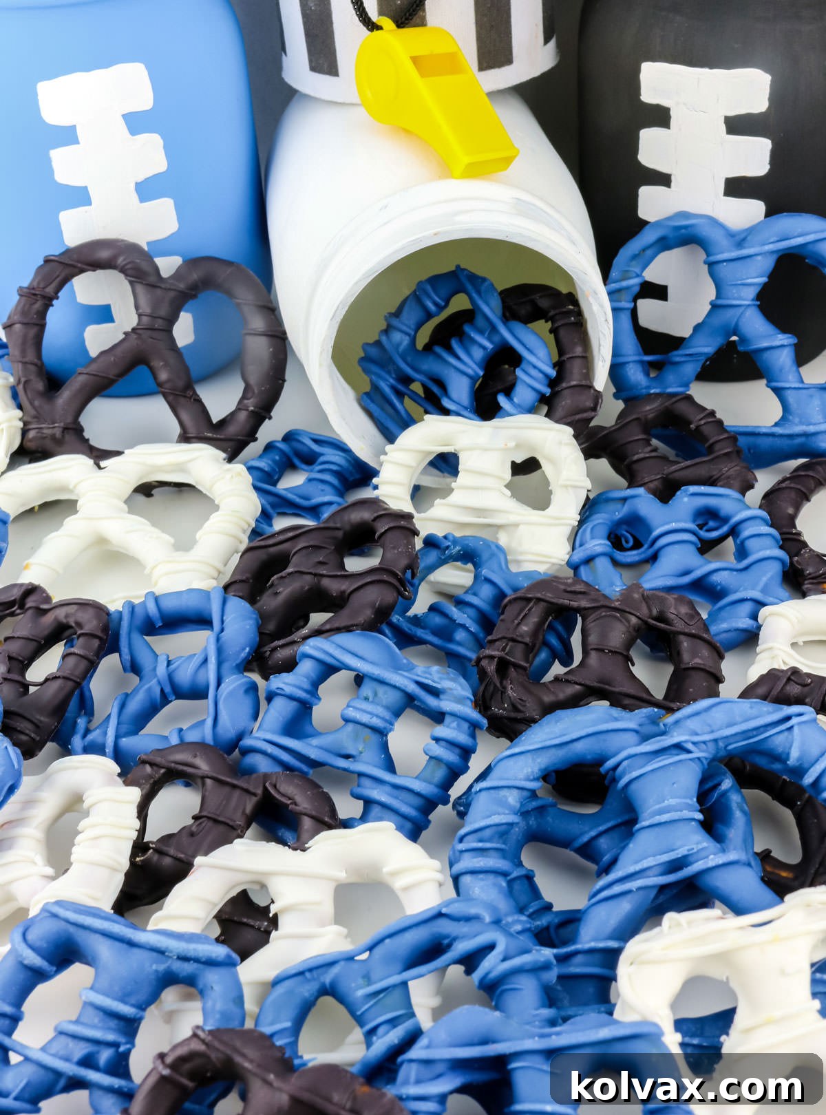 A charming display of Carolina Panthers themed chocolate-covered pretzels, cascading from a white mason jar onto a table.