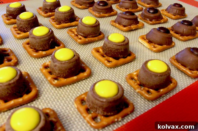 Gently placing gold, black, and white M&M's onto softened Rollo candies on pretzels, creating vibrant Pittsburgh Steelers Pretzel Bites.