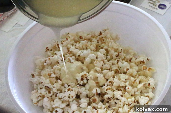 Pouring marshmallow mixture over salted popcorn for even coating.