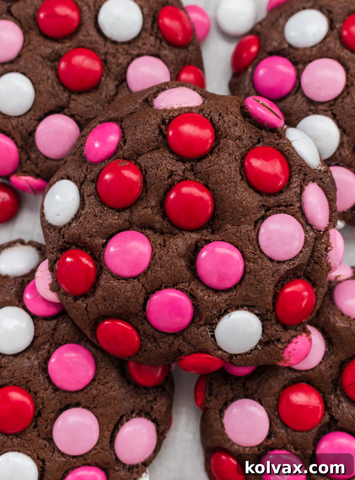 Colorful Valentine M&M Cookies 9 A vibrant closeup of a perfectly baked Valentine's Day M&M Cookie, showcasing an abundance of colorful red, pink, and white M&M's embedded in the rich, dark chocolate cookie.