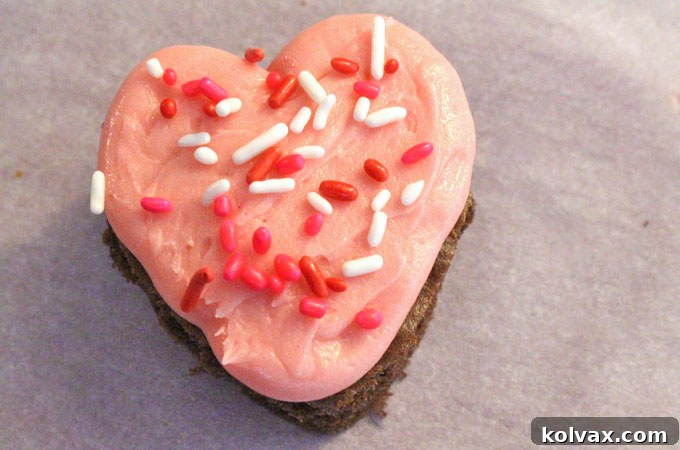 Decorating frosted Valentine's Cake Bites with festive sprinkles.