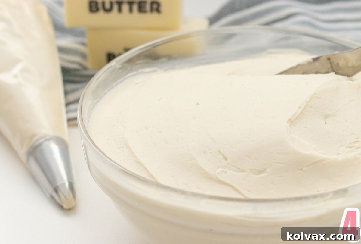 A glass bowl overflowing with creamy homemade Best Buttercream Frosting, with a piping bag filled with frosting ready for decorating, emphasizing its smooth texture.