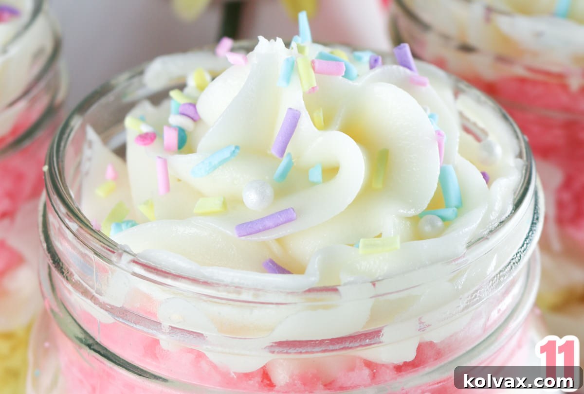 A close-up view of the top of a Springtime Cupcake in a Jar, showing a perfect buttercream swirl adorned with festive pastel sprinkles.